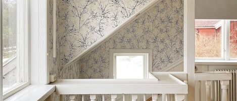 Una escalera con barandillas blancas y un papel tapiz estampado.