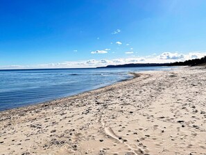A beach with a clear sky, calm water, and footprints in the sand. - 5 Star Holiday Home in Hoor (Hoor)
