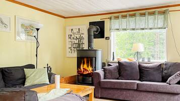 Una sala de estar acogedora con chimenea, un sofá, una mesa y un ventanal con cortinas.