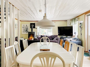 A dining area with a white table and chairs, a fireplace, a sofa, and a television. - 4 Star Holiday Home in Vaddo (Väddö)