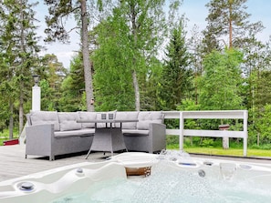 An outdoor hot tub area with a sofa and table, surrounded by trees. - 4 Star Holiday Home in Vaddo (Väddö)