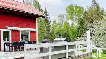 A red building with a deck, outdoor seating, and a barbecue grill.