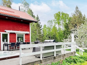 A red building with a deck, outdoor seating, and a barbecue grill.