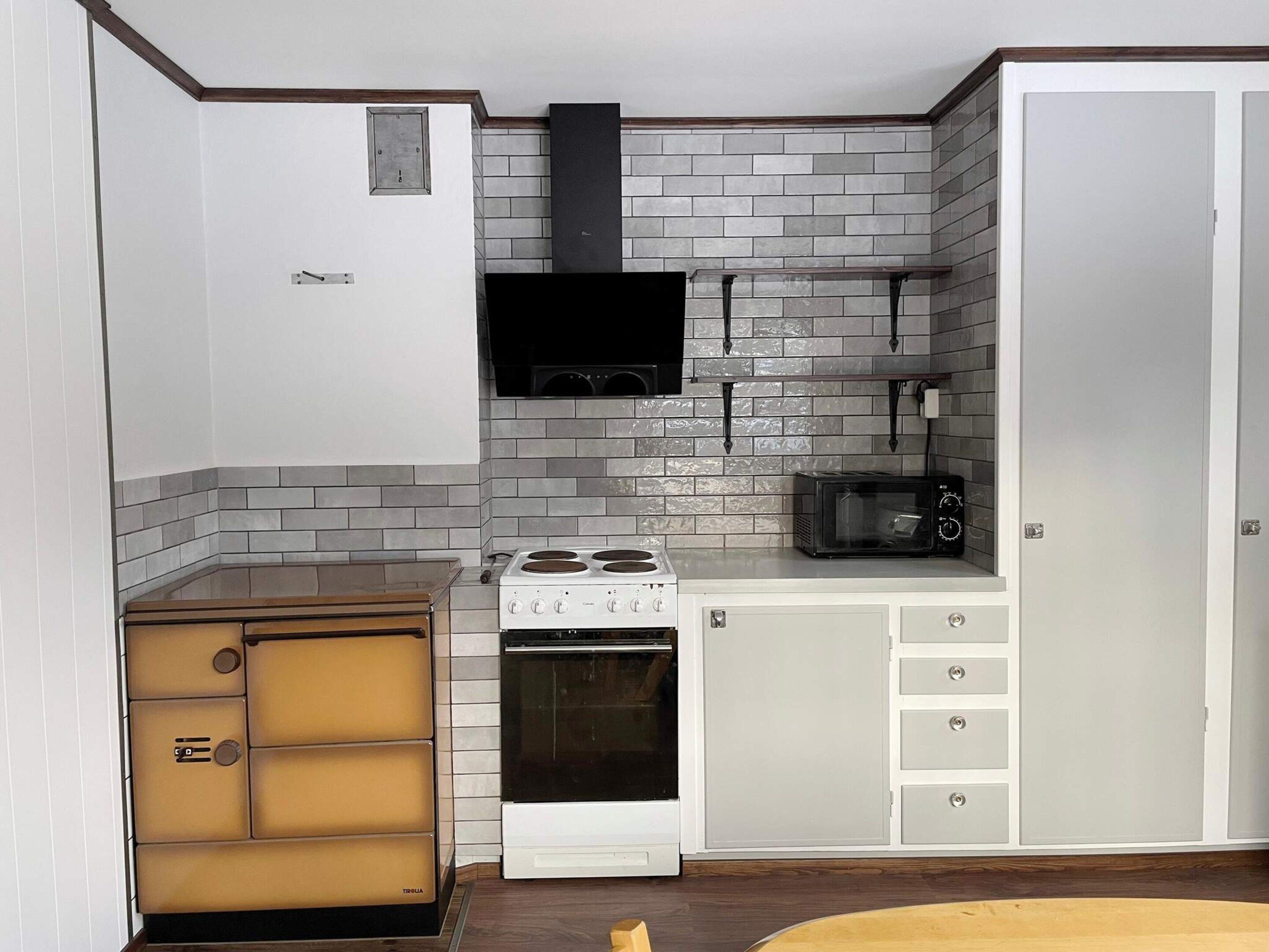 A compact kitchen with a stove, microwave, and a cabinet with drawers.