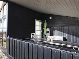 Un espacio de estar al aire libre techado, con una mesa, sillas, una puerta y una ventana.