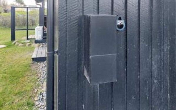 A black metal gate with a rectangular lock and a small circular handle.