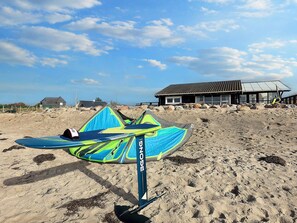 A beach with a kiteboard on a stand, a building with a tiled roof, and a clear sky. - 4 Star Holiday Home in Karrebaeksminde (Karrebæksminde)