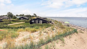 Um imóvel costeiro com várias casas, uma praia arenosa e vista para o mar.