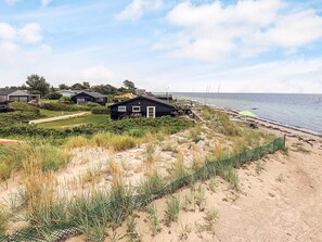 A coastal property with multiple houses, a sandy beach, and a view of the sea. - 4 Star Holiday Home in Karrebaeksminde (Karrebæksminde)