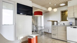 A modern kitchen with a dining area, a TV mounted on the wall, and a red pendant light. - 4 Person Holiday Home in Bogense (Bogense)