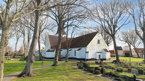 A white church with a red roof, surrounded by trees and a well-maintained lawn. - 4 Person Holiday Home in Bogense (Bogense)