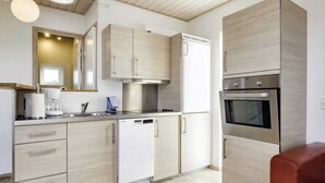 A modern kitchen with light wood cabinetry, a built-in dishwasher, a coffee maker, and a stainless steel oven. - 4 Person Holiday Home in Bogense (Bogense)