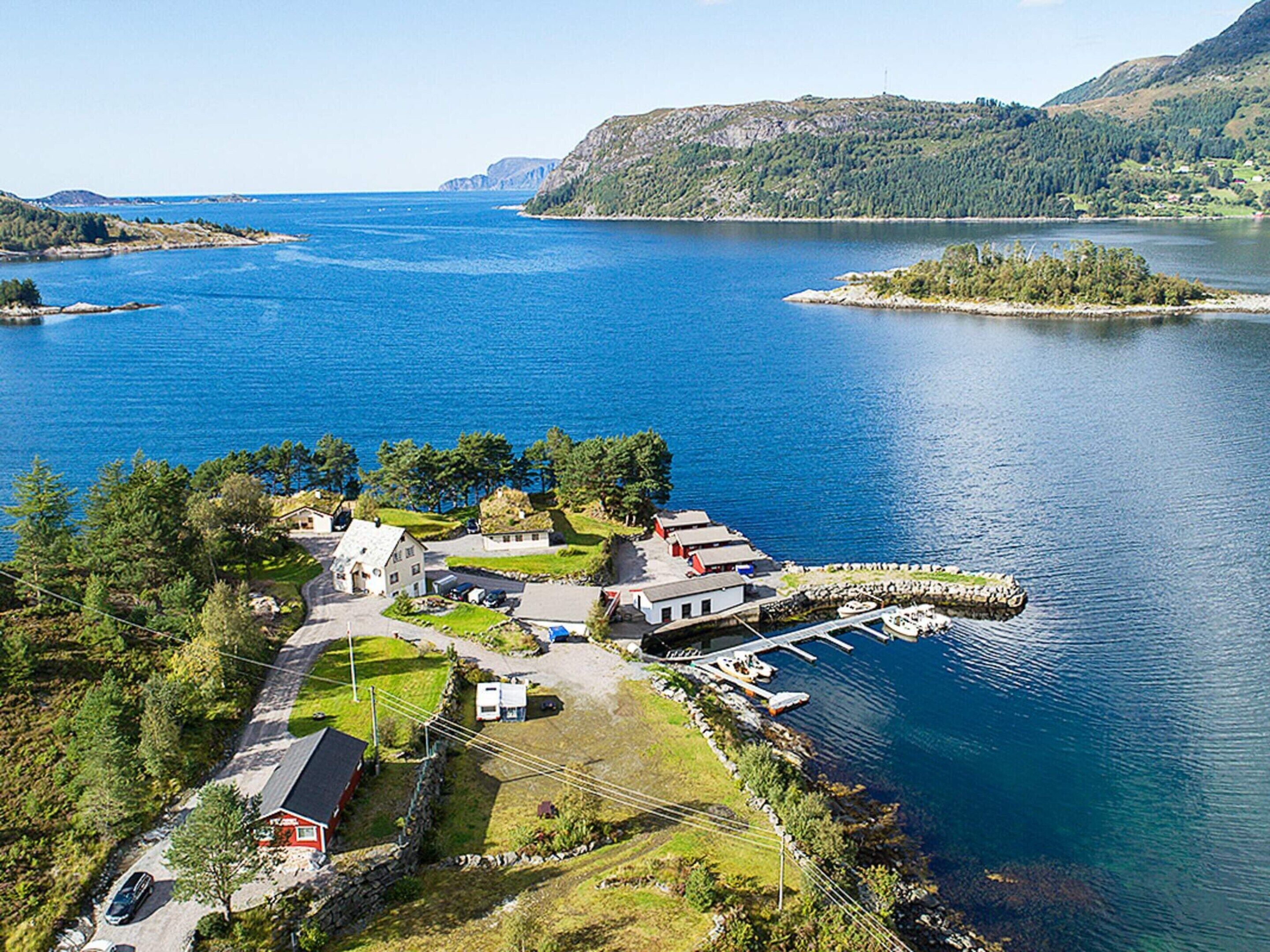 An aerial view of a lakeside property with a dock, boats, and a small building.