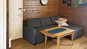 A room with a grey sofa, a wooden coffee table, a wooden floor, and a clock on the wall. - 3 Person Holiday Home in Flatraket (Stad)