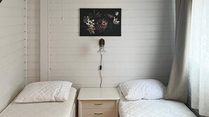 A small, single-room accommodation with two single beds, a bedside table, a wall-mounted power outlet, and a floral artwork above the bed. - 3 Person Holiday Home in Flatraket (Stad)