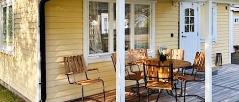 A small house with a porch, a dining table with chairs, and a door.