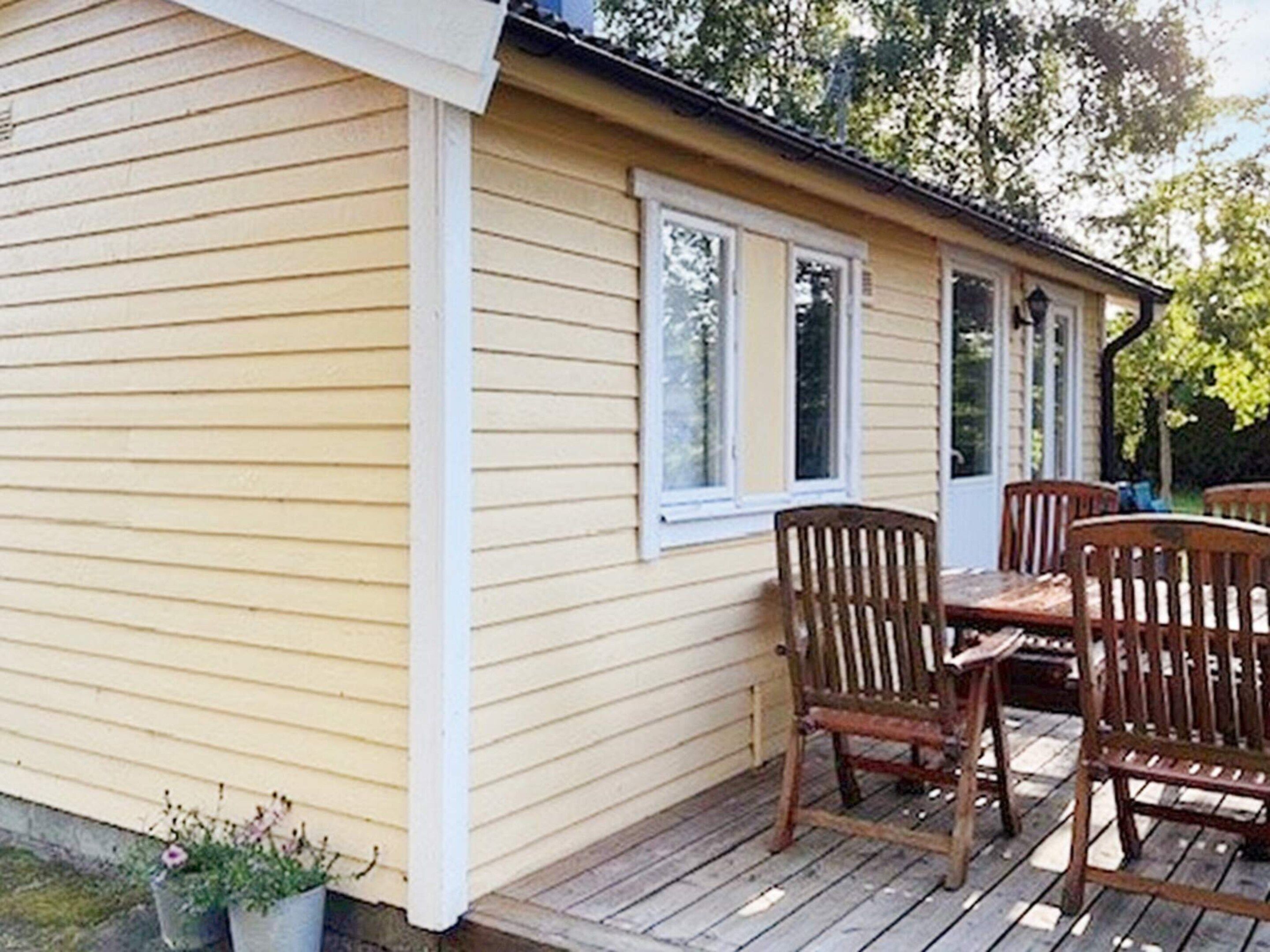 Une terrasse en bois avec une table et des chaises, une fenêtre et une porte.