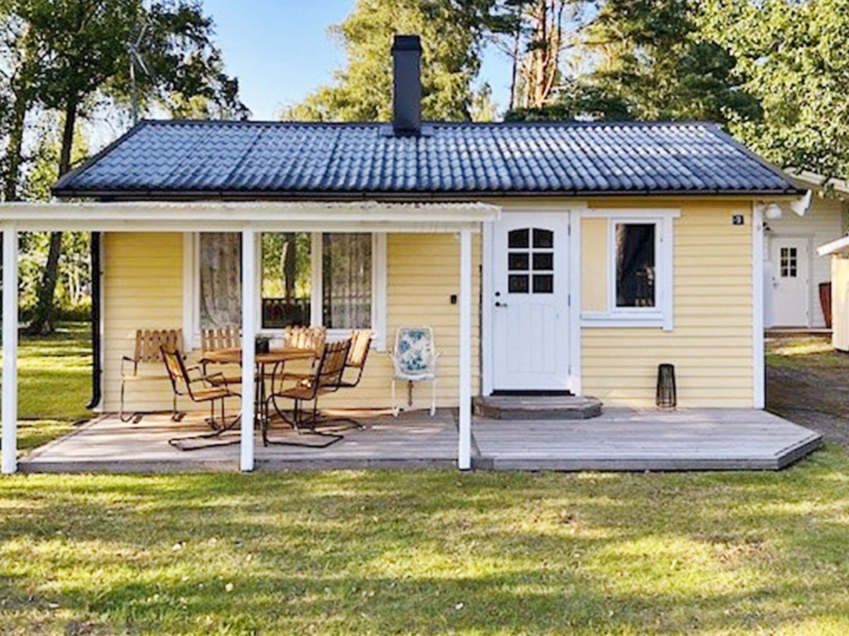Ein kleines gelbes Haus mit überdachter Veranda, Schornstein und einer Tür mit Fenstern.