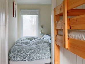 A bunk bed with a patterned blanket, a bedside lamp, and a window with a white blind. - 6 Person Holiday Home in Mellbystrand (Mellbystrand)