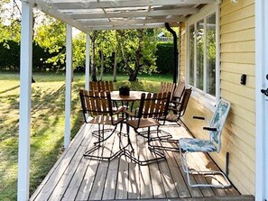 A covered patio with a wooden deck, a round table, and multiple chairs. - 6 Person Holiday Home in Mellbystrand (Mellbystrand)