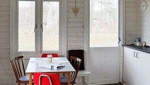 A room with a dining table, chairs, a kitchen area, and two windows. - 6 Person Holiday Home in Mellbystrand (Mellbystrand)