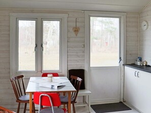 A room with a dining table, chairs, a kitchen area, and two windows. - 6 Person Holiday Home in Mellbystrand (Mellbystrand)