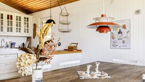 Ein Holztisch mit Stühlen, eine Vase mit getrockneten Blumen und eine Pendelleuchte.