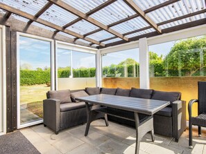 A covered patio area with wicker furniture and a glass door leading to a garden. - 4 Person Holiday Home in Nordborg (Nordborg)