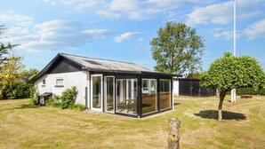 A modern house with a glass-enclosed porch, a metal roof, and a well-maintained lawn. - 4 Person Holiday Home in Nordborg (Nordborg)