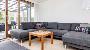 A modern living room with a grey sectional sofa, a wooden coffee table, and colorful patterned cushions. - 4 Person Holiday Home in Nordborg (Nordborg)