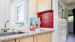 A modern kitchen with a granite countertop, stainless steel sink, and wooden cabinets. - 4 Person Holiday Home in Nordborg (Nordborg)