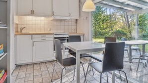 Een moderne keuken met witte kastjes, een dubbele oven en een eethoek met een tafel en stoelen.