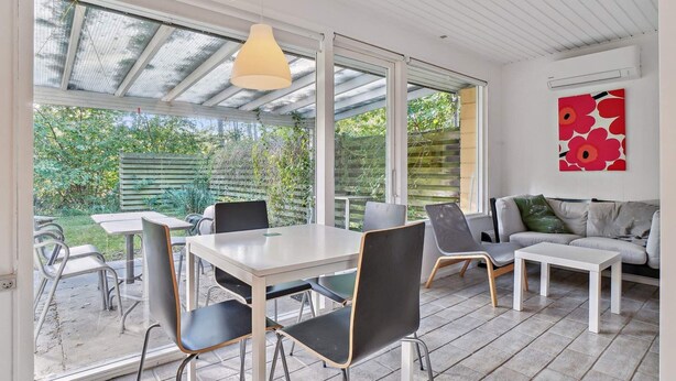 Een modern terras met een eettafel, stoelen en een bank.