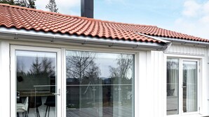 A modern house with a tiled roof, large sliding glass doors, and a wooden deck. - 4 Star Holiday Home in Uddevalla (Uddevalla)