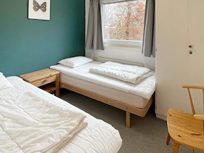 A single-bed room with a wooden frame, a small bedside table, a chair, and a window with curtains. - 4 Star Holiday Home in Olofstrom (Olofström)