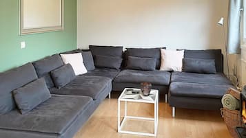 A modern living room with a sectional sofa, a small white coffee table, and a large mirror on the wall.