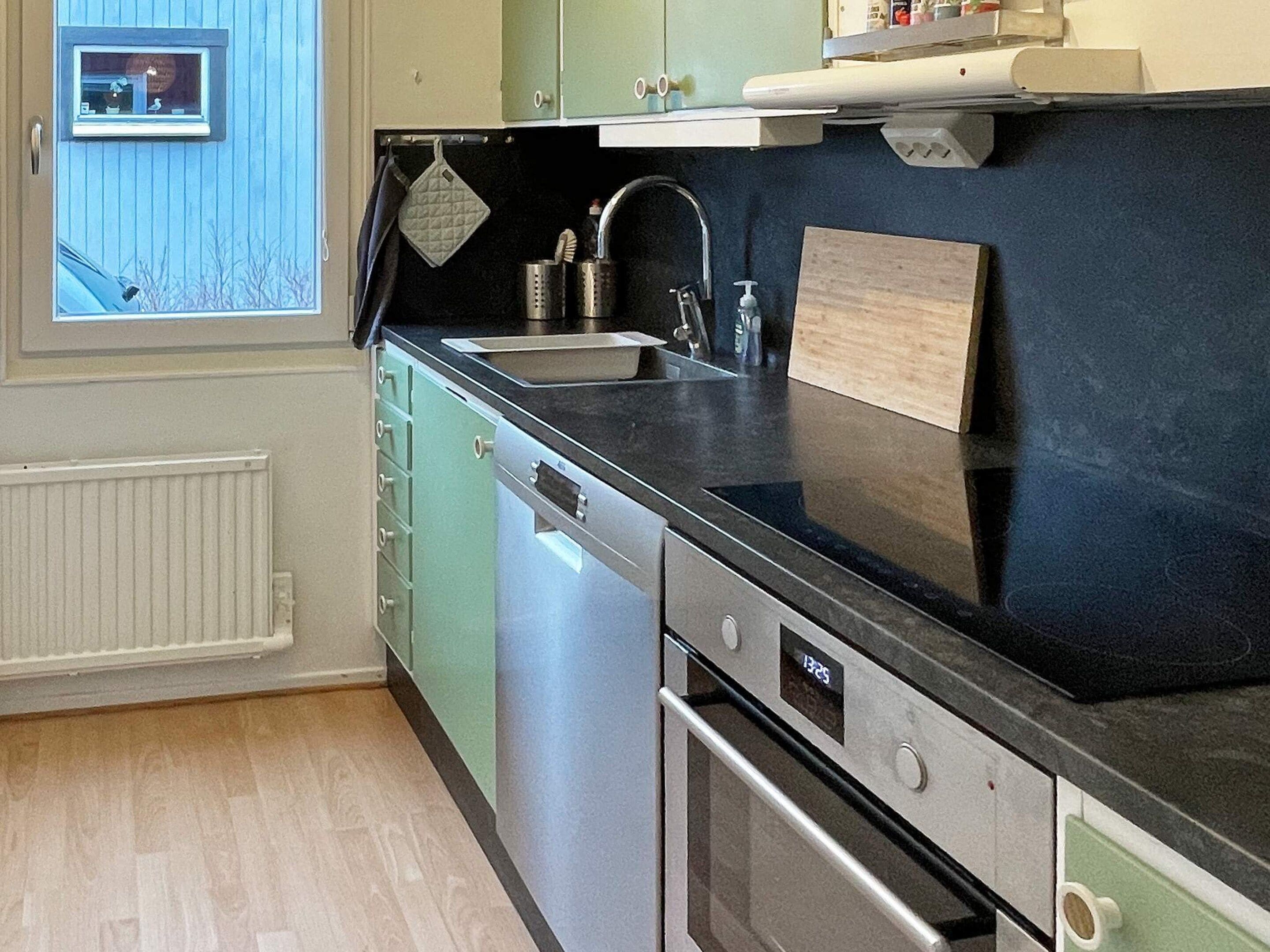 A kitchen with a dishwasher, oven, and a window with a view of the outside.