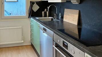 A kitchen with a dishwasher, oven, and a window with a view of the outside.