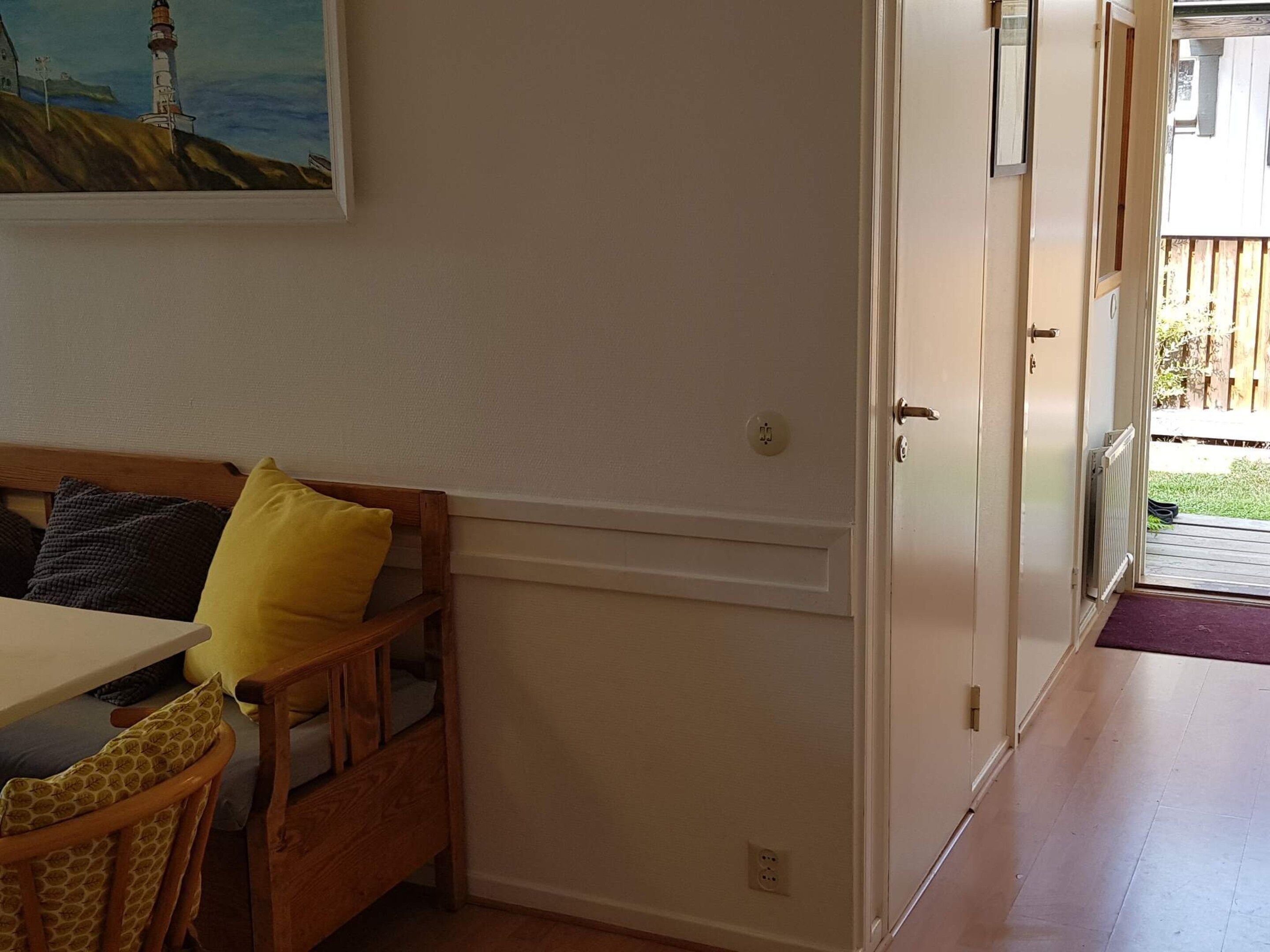 A room with a wooden bench, a table, and a door leading to an outdoor area.