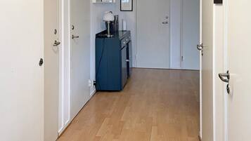 A hallway with wooden flooring, white doors, and a blue cabinet with a lamp.