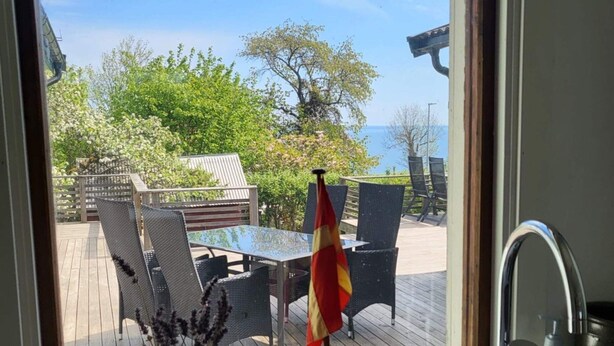Une terrasse dotée de mobilier d’extérieur, d’un drapeau et offrant une vue sur la mer.