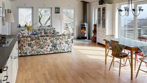 Un vaste espace de vie doté d’un plancher en bois, d’un canapé à motifs floraux, d’une table à manger avec des chaises et d’une cheminée.