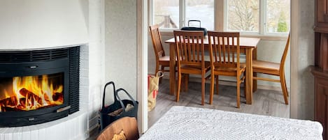Une pièce chaleureuse avec une cheminée, une table à manger en bois et des chaises.