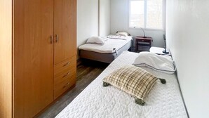 A bedroom with two beds, a wardrobe, a desk, and a window. - 4 Person Holiday Home in Lekeryd (Lekeryd)