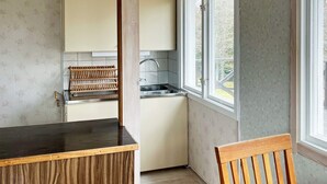 A compact kitchen with a built-in sink, a wooden chair, and a window providing natural light. - 4 Person Holiday Home in Lekeryd (Lekeryd)