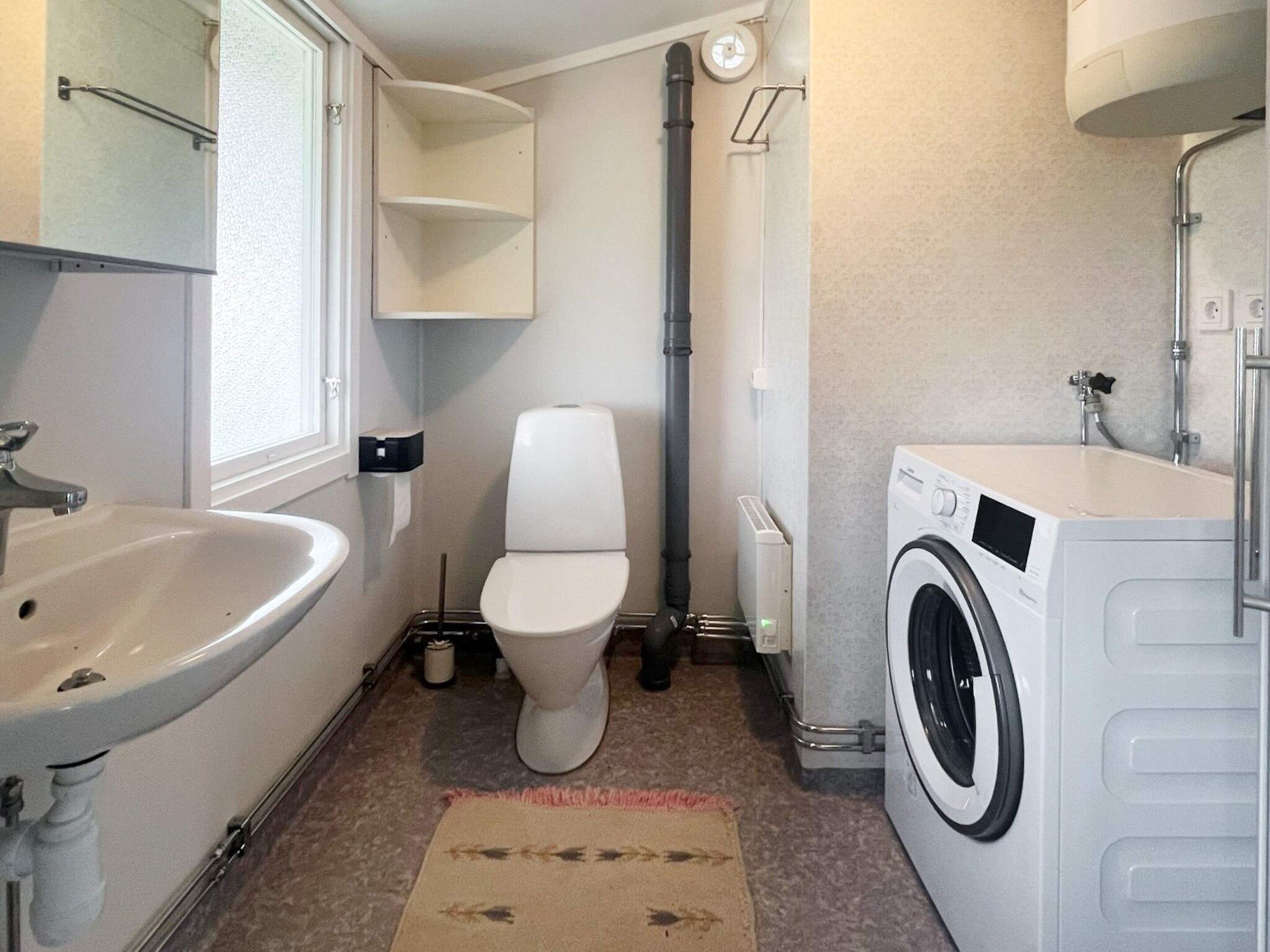A compact bathroom with a sink, toilet, and washing machine.