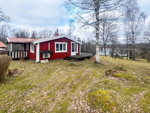 Un bâtiment rouge doté d’un porche et d’une cheminée, entouré d’une cour verdoyante et d’arbres.