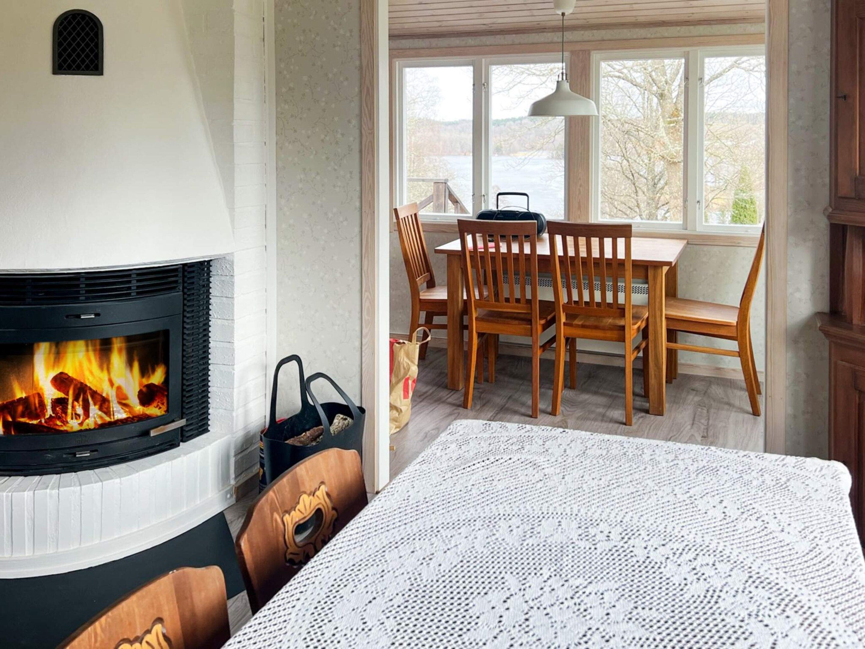 A room with a fireplace, wooden dining table, and chairs.