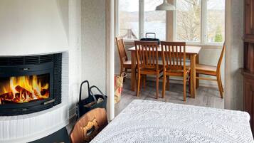 A room with a fireplace, wooden dining table, and chairs.