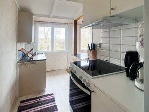 A compact kitchen with a stove, sink, and window.
